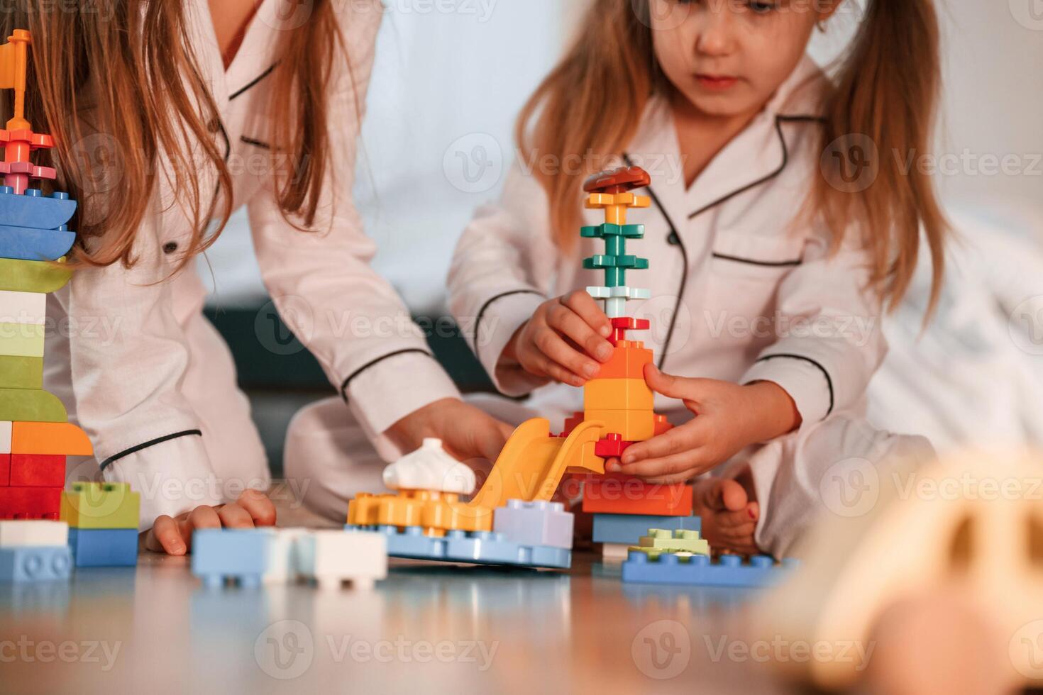 Many of the blocks of plastic construction toys. Two, little girls are playing and having fun together in domestic room photo