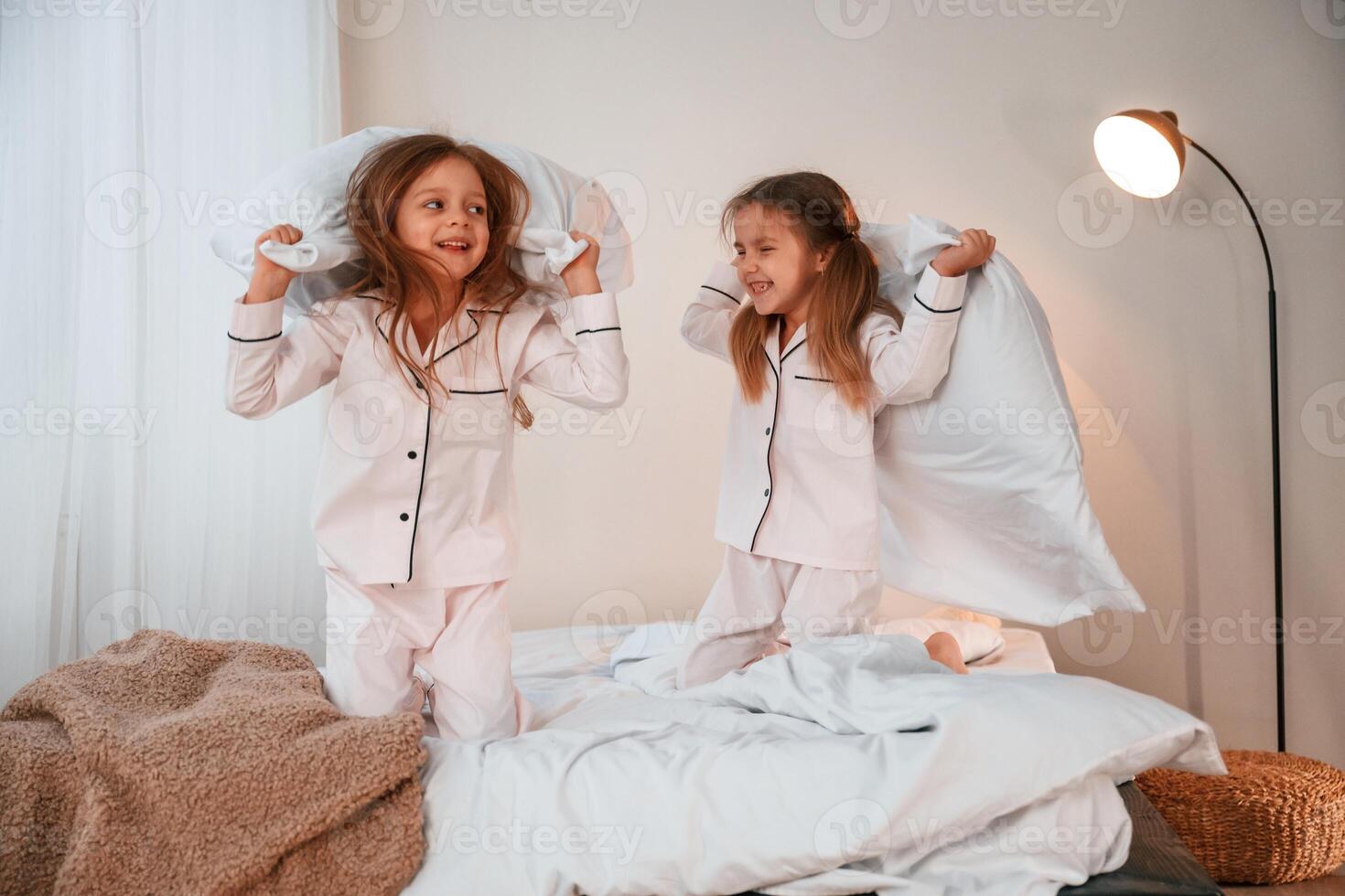 Active weekend... On the bed with pillows. Two little girls are playing and having fun together in domestic room photo