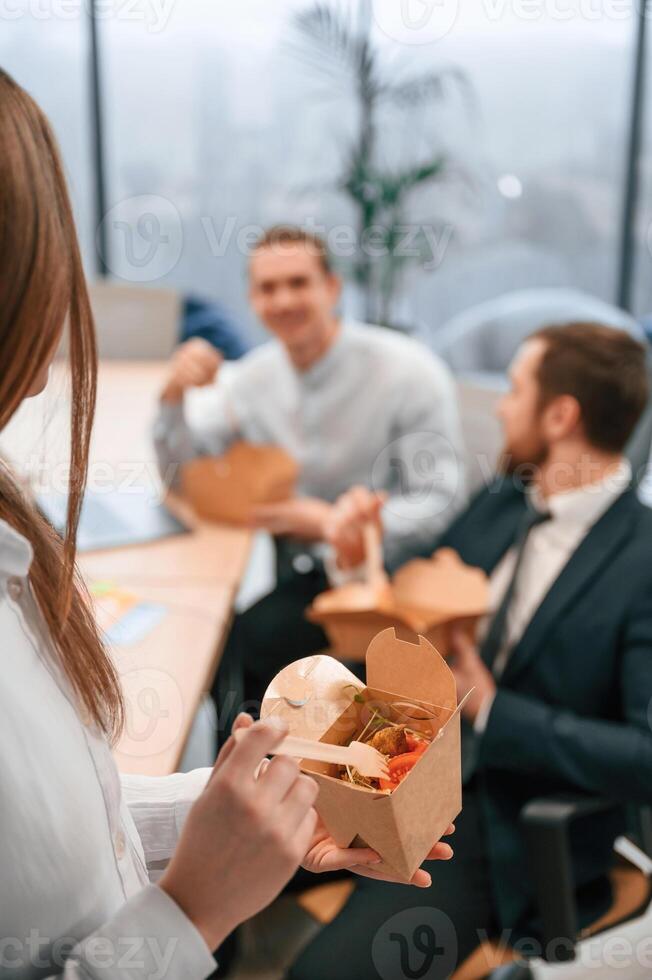 Close up view of meal.. Group of coworkers are eating food from eco boxes in the office together photo