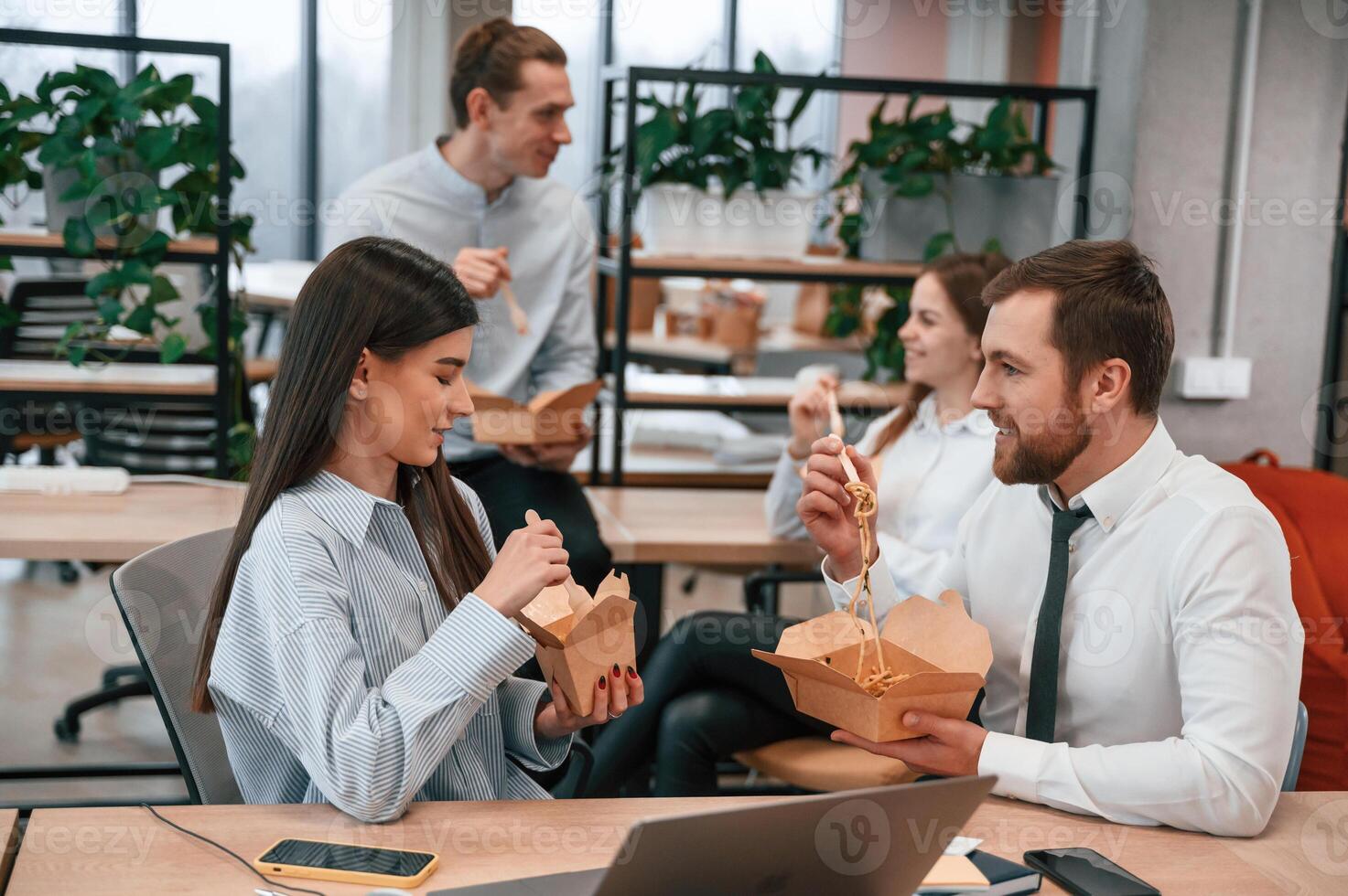 Casual conversation. Group of, coworkers are eating food from eco boxes in the office together photo