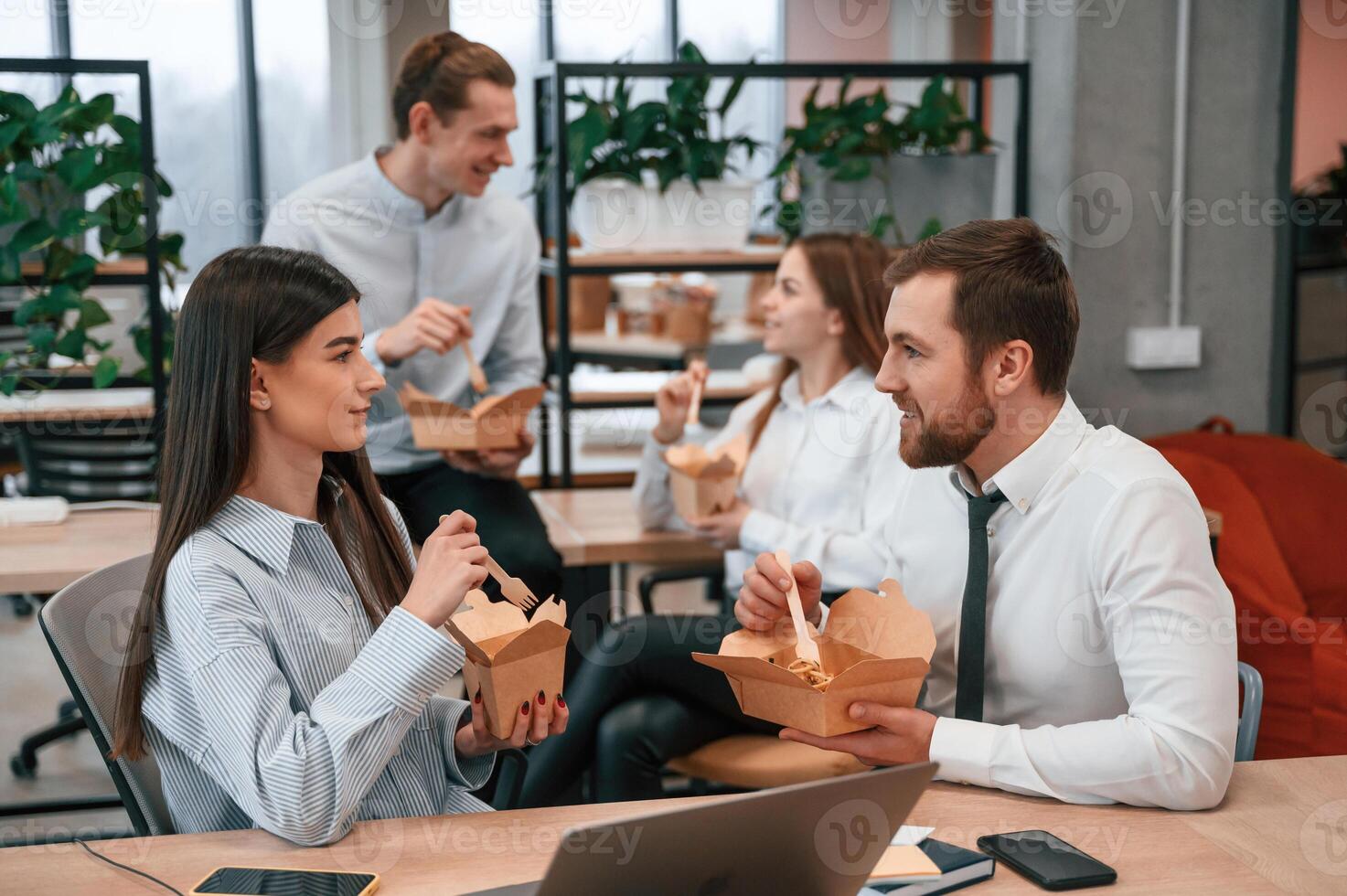 Casual, conversation. Group of coworkers are eating food from eco boxes in the office together photo