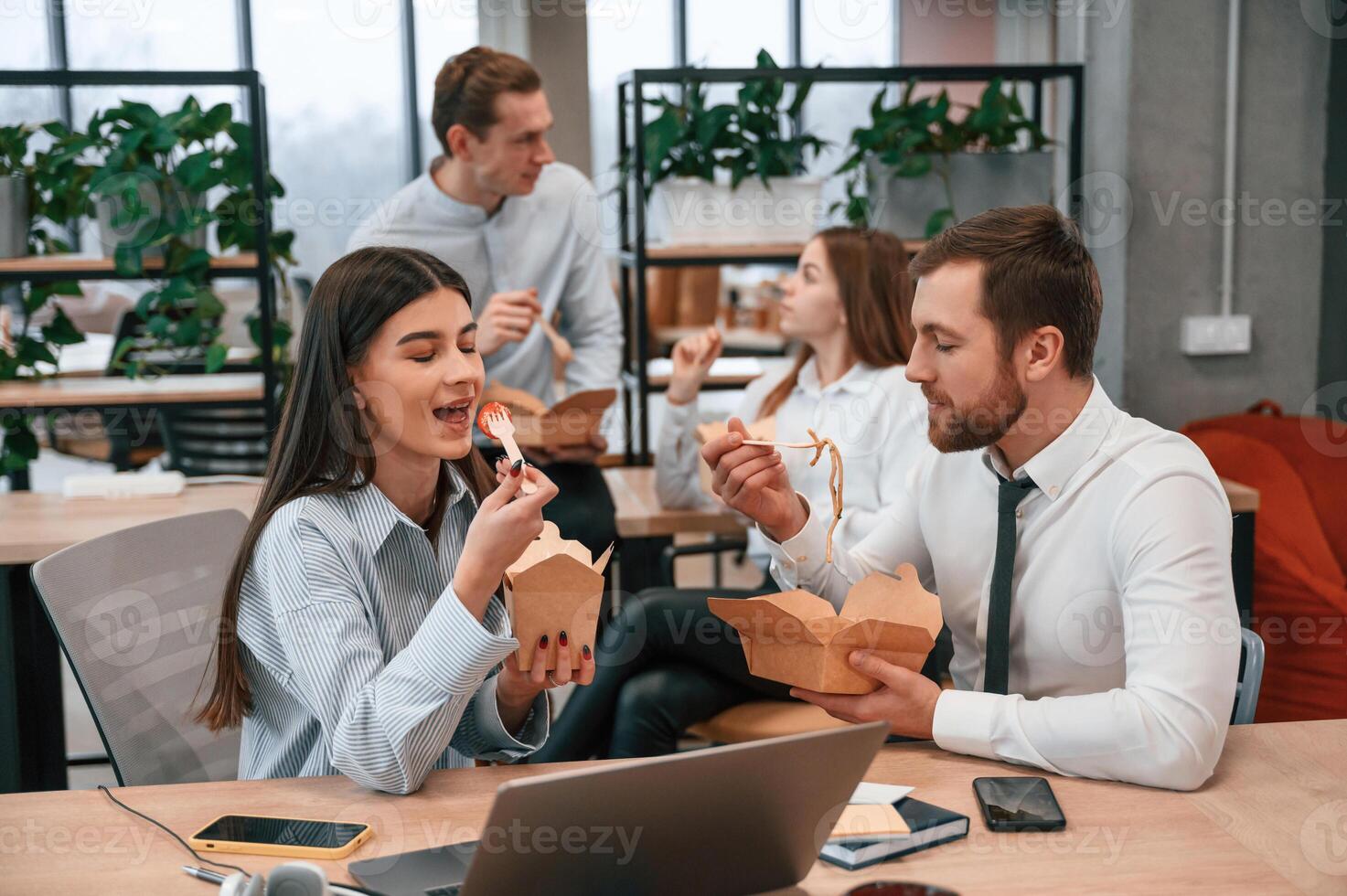 Having, a conversation.. Group of coworkers are eating food from eco boxes in the office together photo