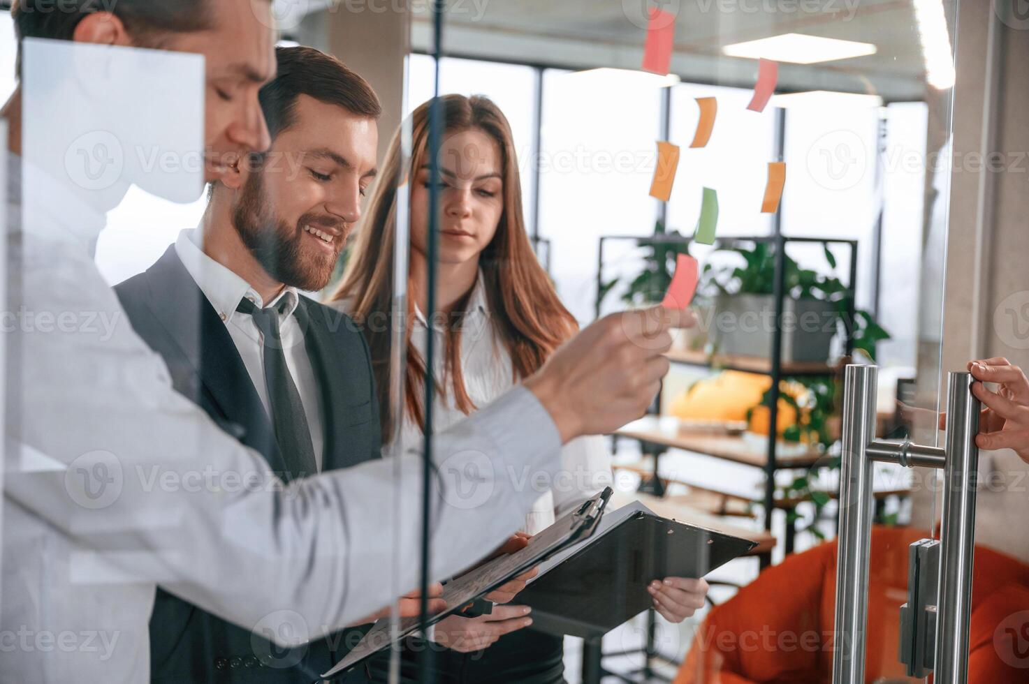 Group, of coworkers in the office is standing together and putting stickers on the glass photo