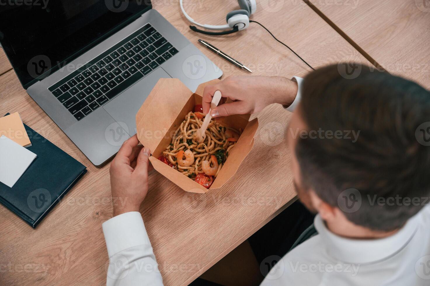 Top, view. Businessman in formal clothes is in the office eating udon that is in the eco box photo