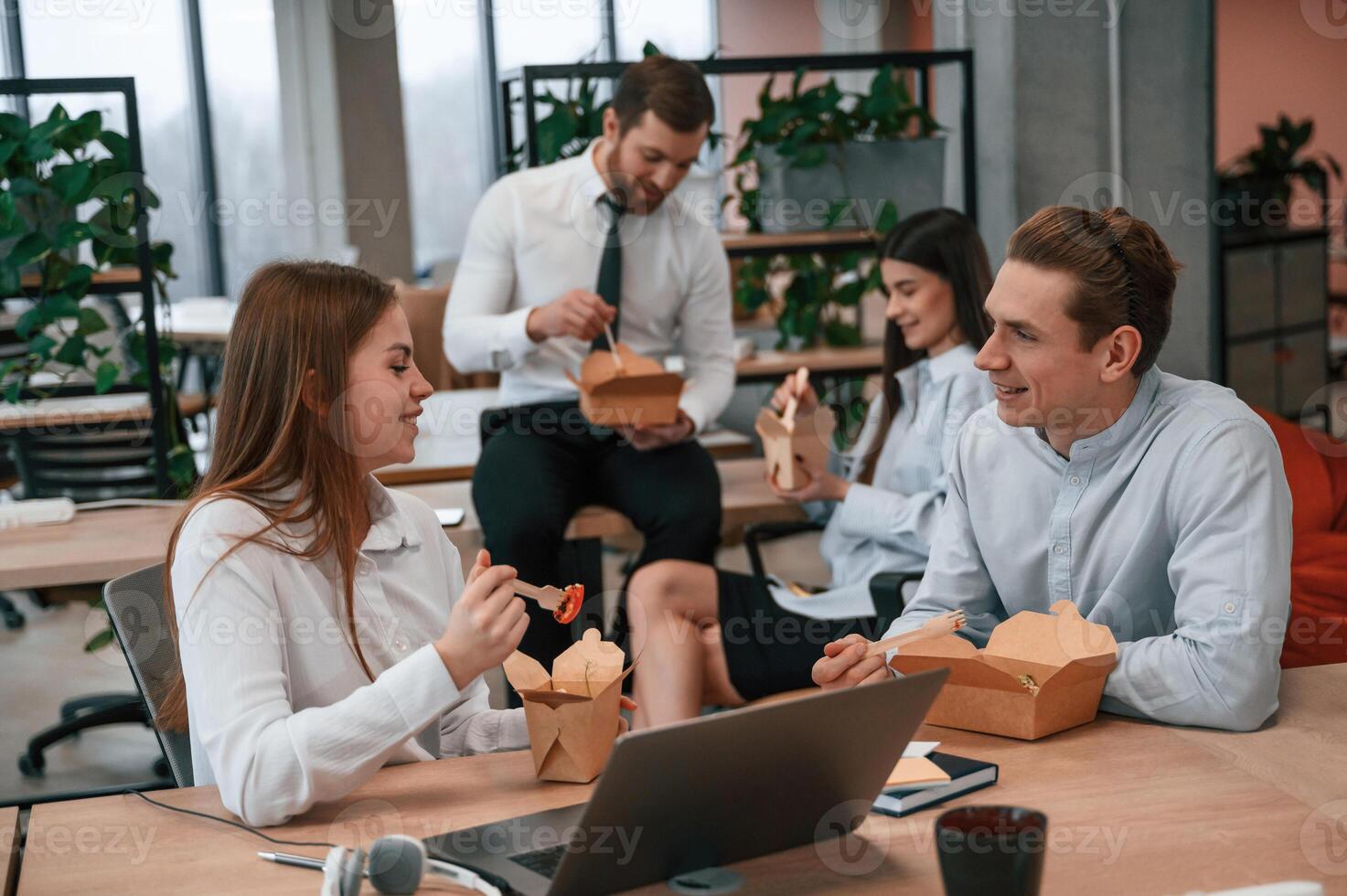 Talking, having, a break.. Group of coworkers are eating food from eco boxes in the office together photo