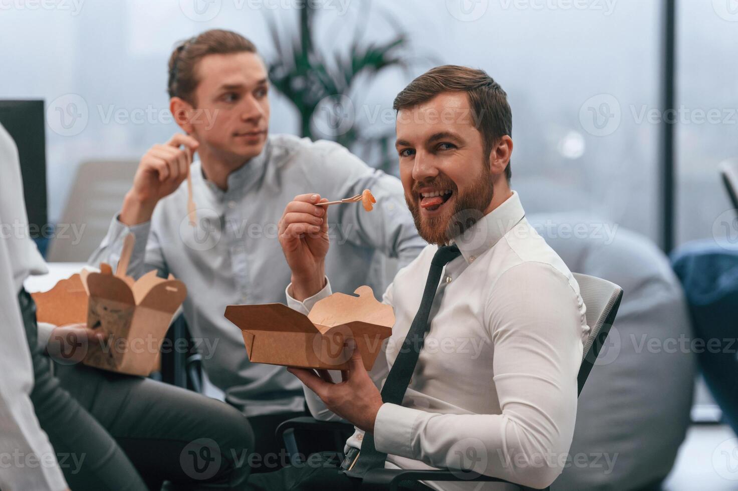 Coworkers are sitting in the office and eating food, from eco boxes photo