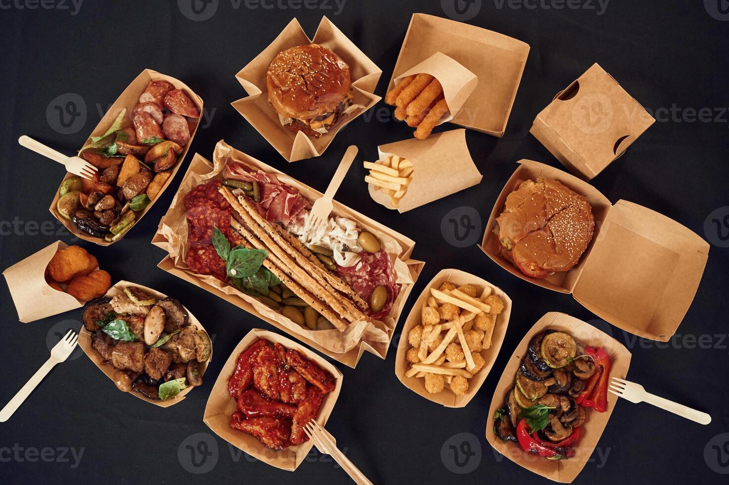 On the black colored table.. Top view, of food on it. Meat, vegetables, French fries, burger, mushrooms photo