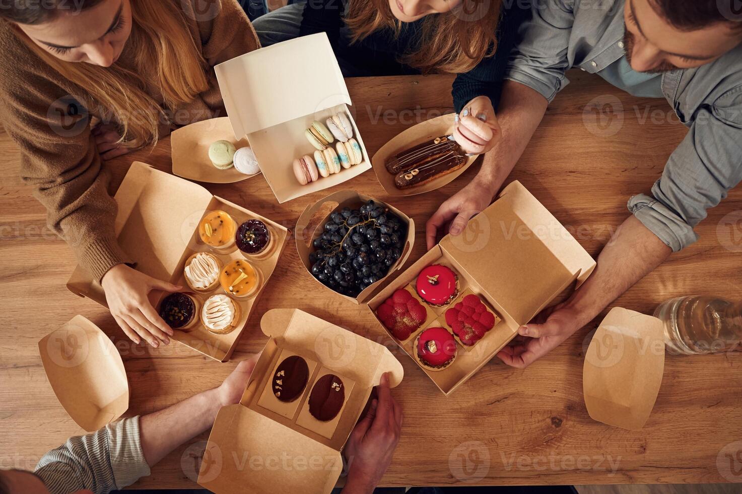 Top view, of table with food on it, hands of the people taking it, eating. Macarons, blueberries, desserts, pastry meal photo