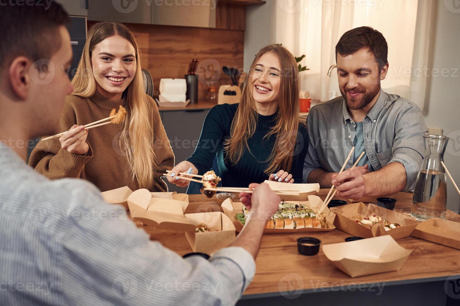 Casual conversation. Friends, are sitting indoors at home and eating sushi together photo