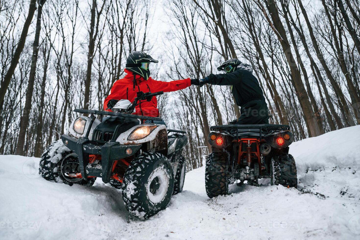 Knocking the fists. Two people are riding ATV in, th,e winter forest photo