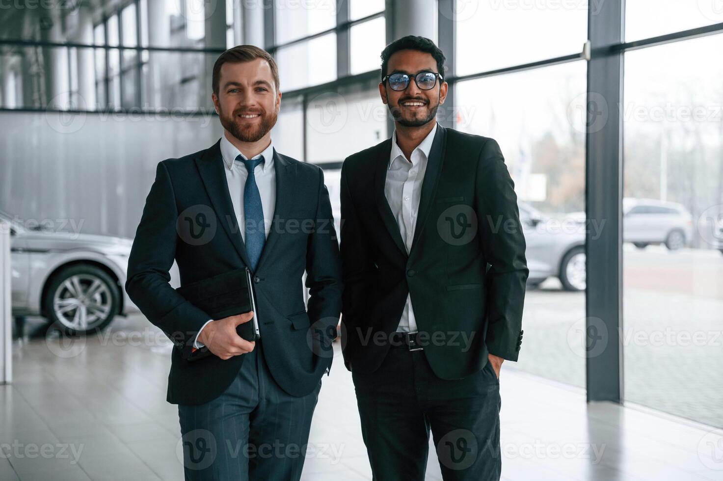 Standing and smiling., Two businessmen are working together in the car showroom photo