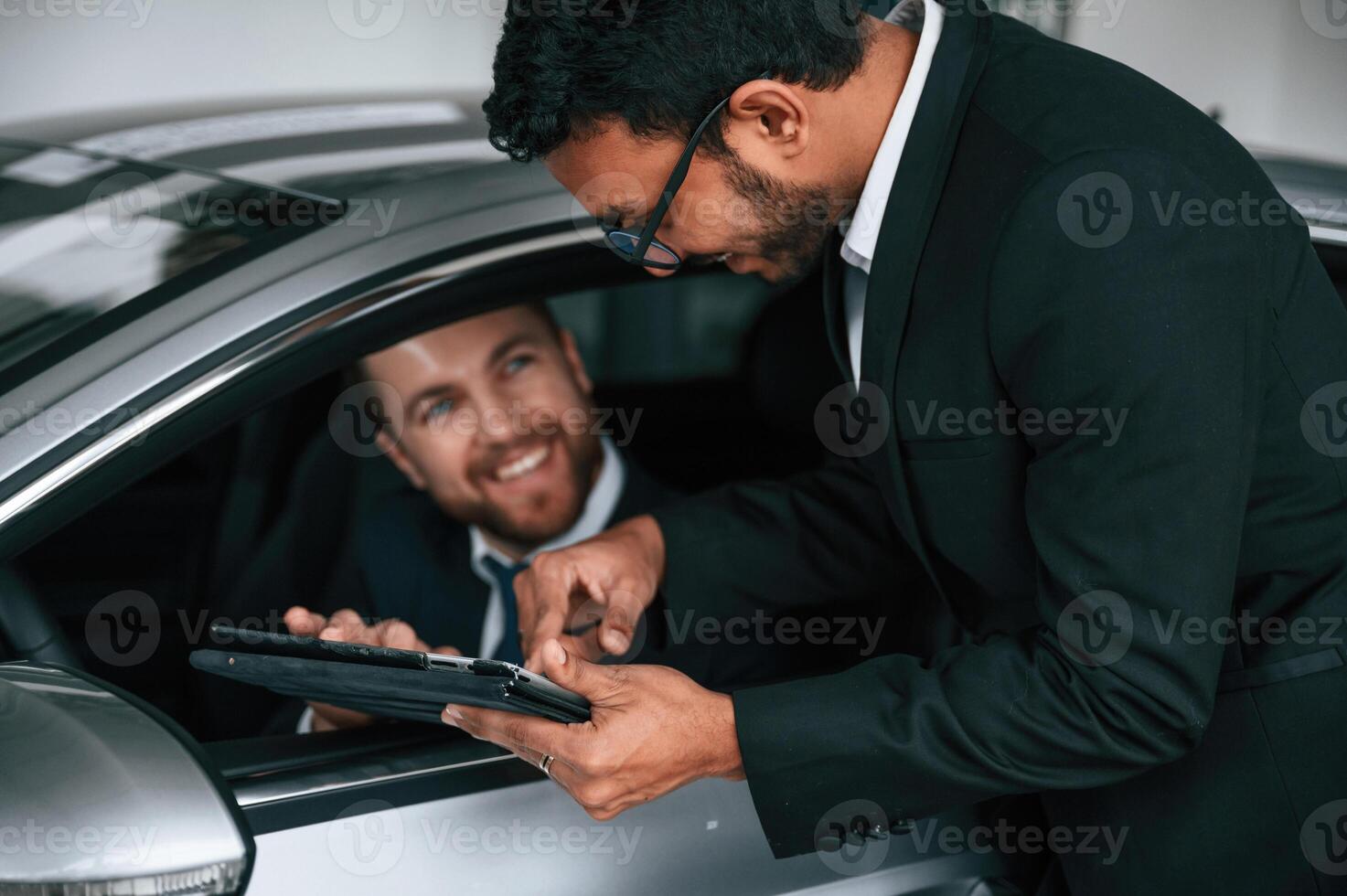 Man is, sitting in the new automobile, consultant is showing details and data on graphic tablet to customer photo