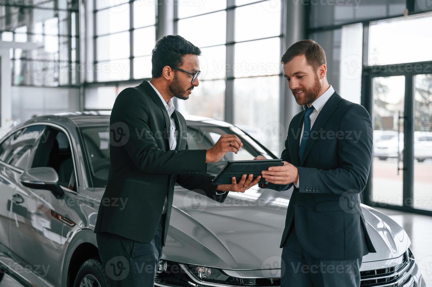 Using, graphic tablet. Man is consulting the customer in the car showroom photo