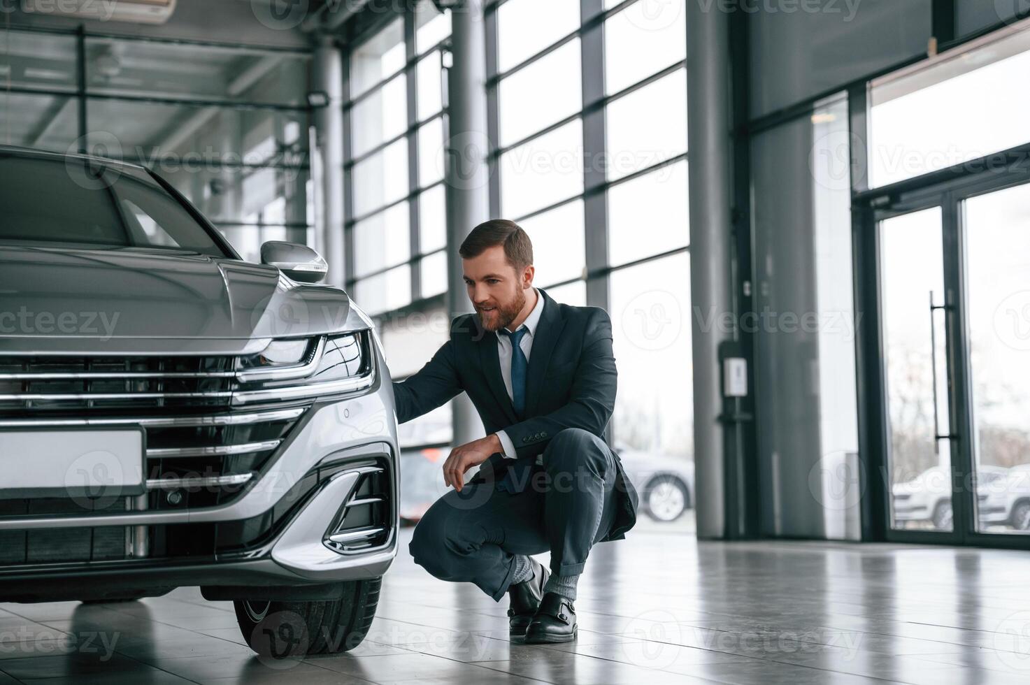 Man in, suit and tie is sitting and checking quality of the vehicle in the car showroom photo