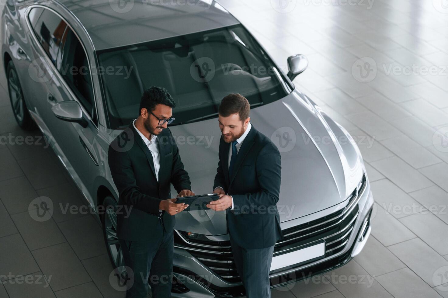Using graphic ,tablet. Man is consulting the customer in the car showroom photo