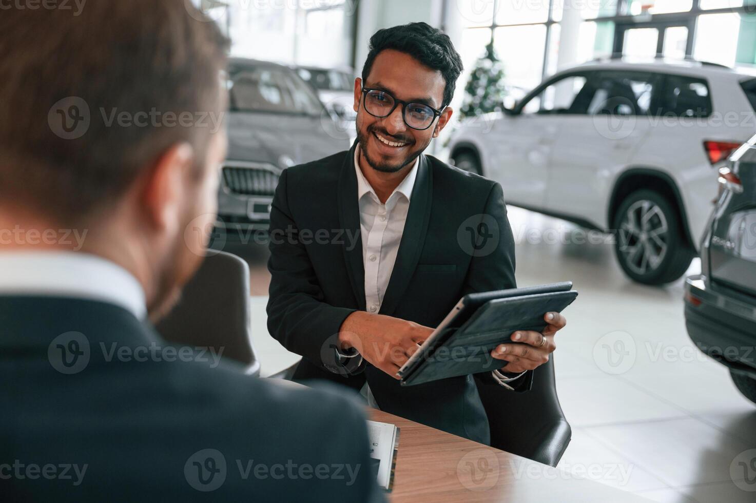 Using ,graphic tablet. Man is consulting the, customer in the car showroom photo