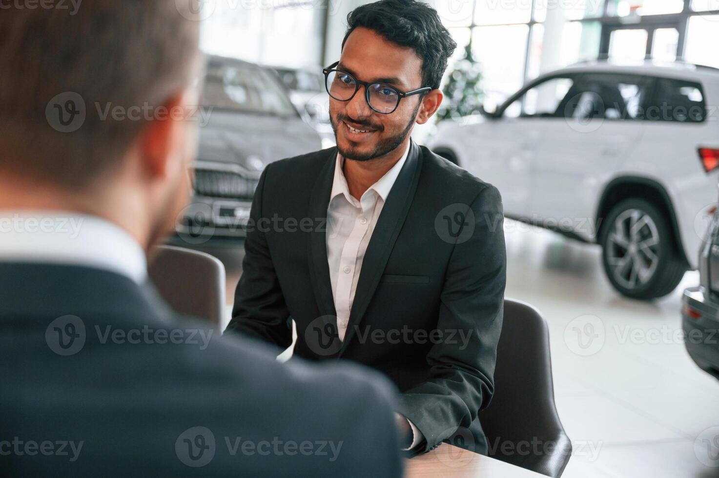 Sitting, by ,the table. Man is consulting the customer in the car showroom photo