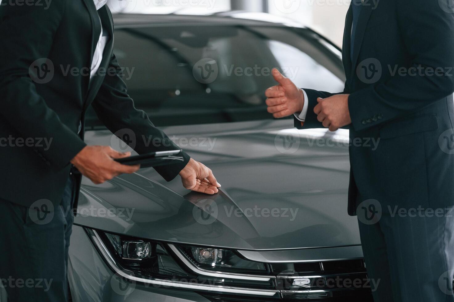 Near grey ,colored automobile. .Two businessmen are working together in the car showroom photo