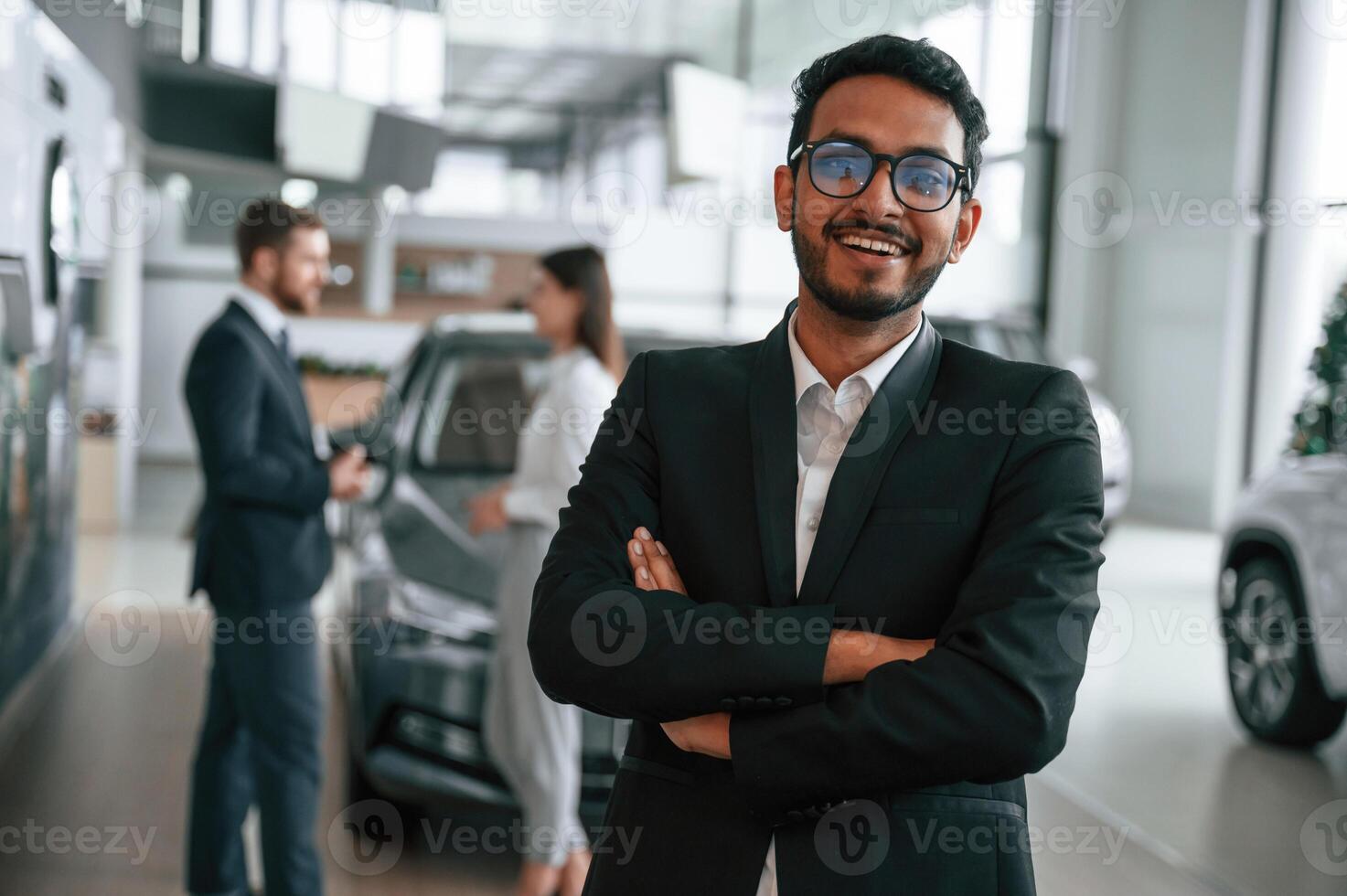 Man standing in front of his coworkers. Three people are working together in the car showroom photo