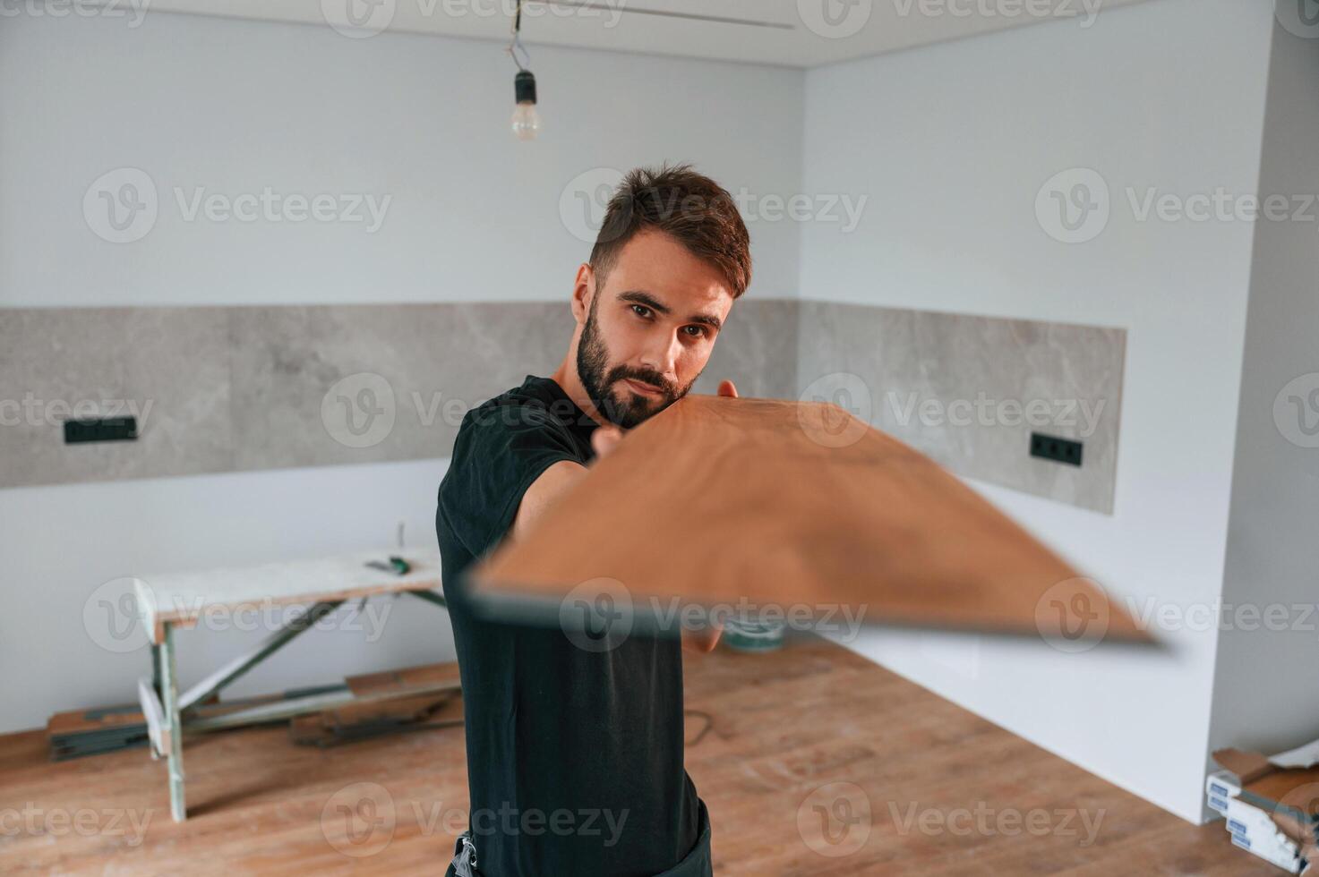 Looking ,at the length of, the plank. Man is installing new laminated wooden floor photo