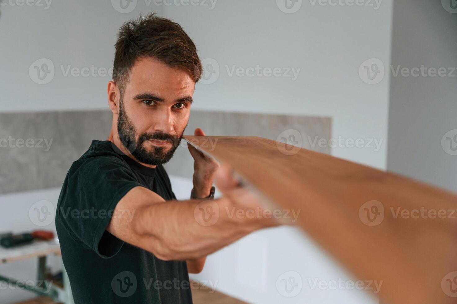 Looking, at the length of the plank. Man is installing new laminated wooden floor photo