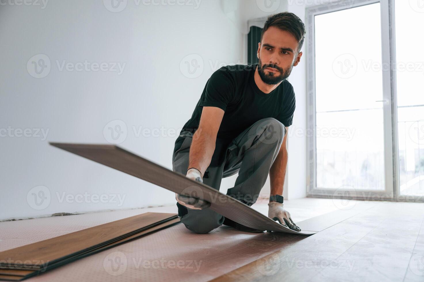 Fitting, the planks.. Man is installing new laminated wooden floor photo