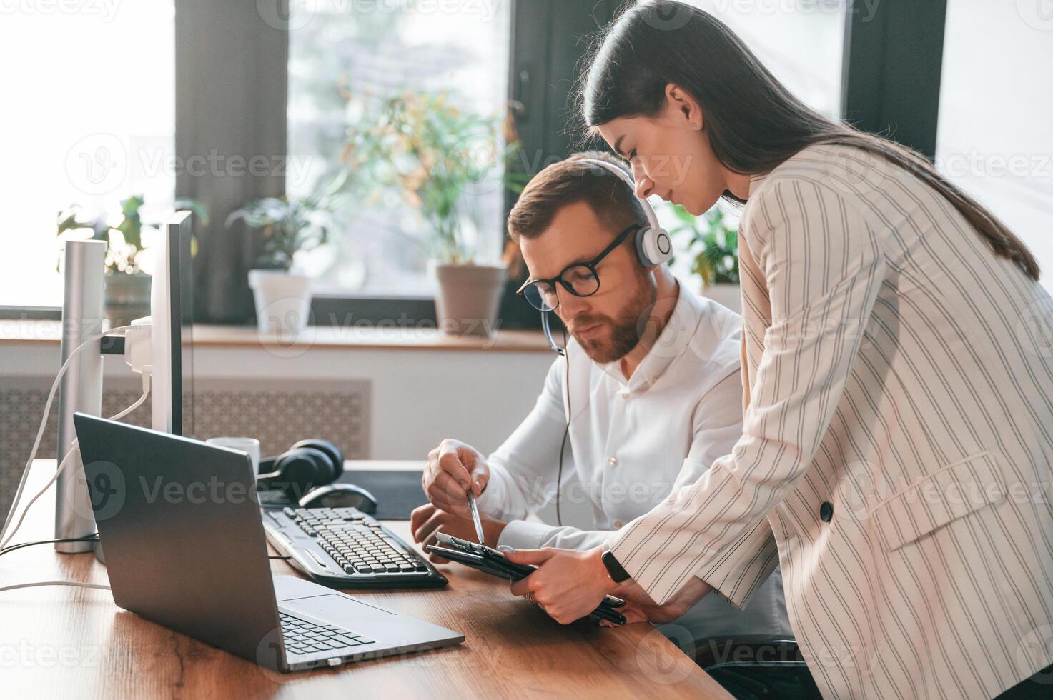 Showing, information on tablet. Two employees are working together in the modern office photo