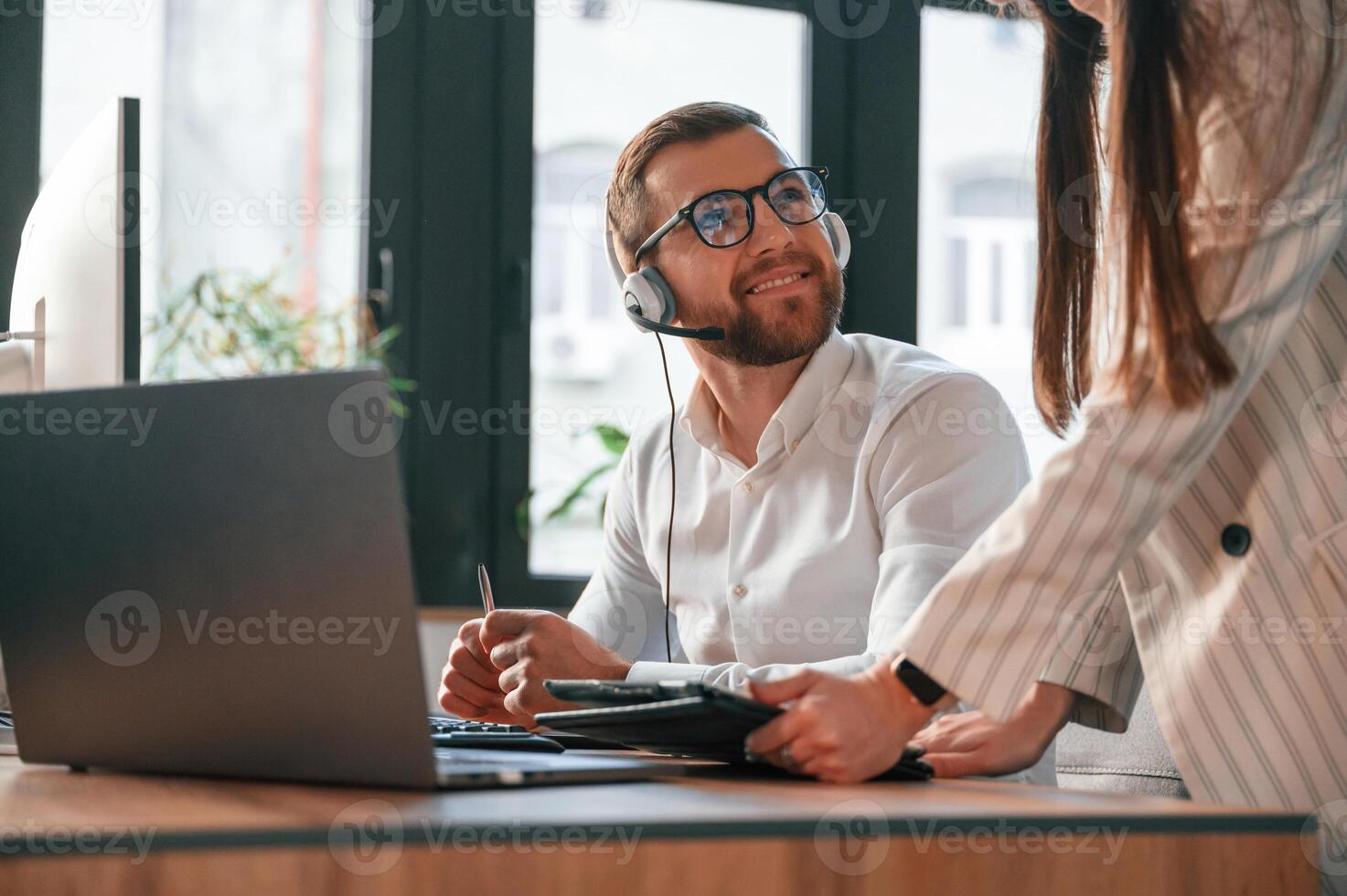 Showing ,information on tablet. Two employees are working together in the modern office photo