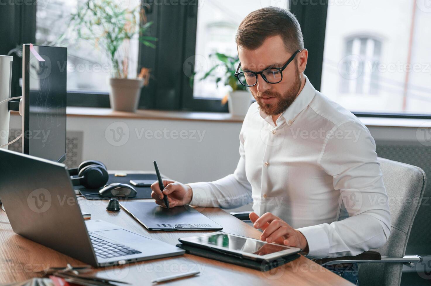 Using, tablet. Man in formal clothes is working in the modern office photo