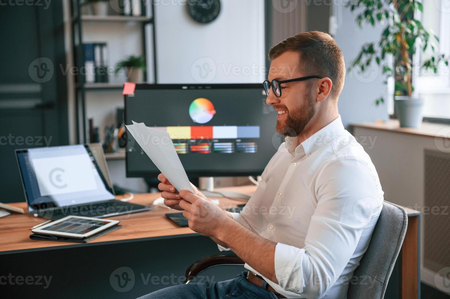 Graphic ,designer is sitting. Man in formal clothes is working in the modern office. Using computer photo