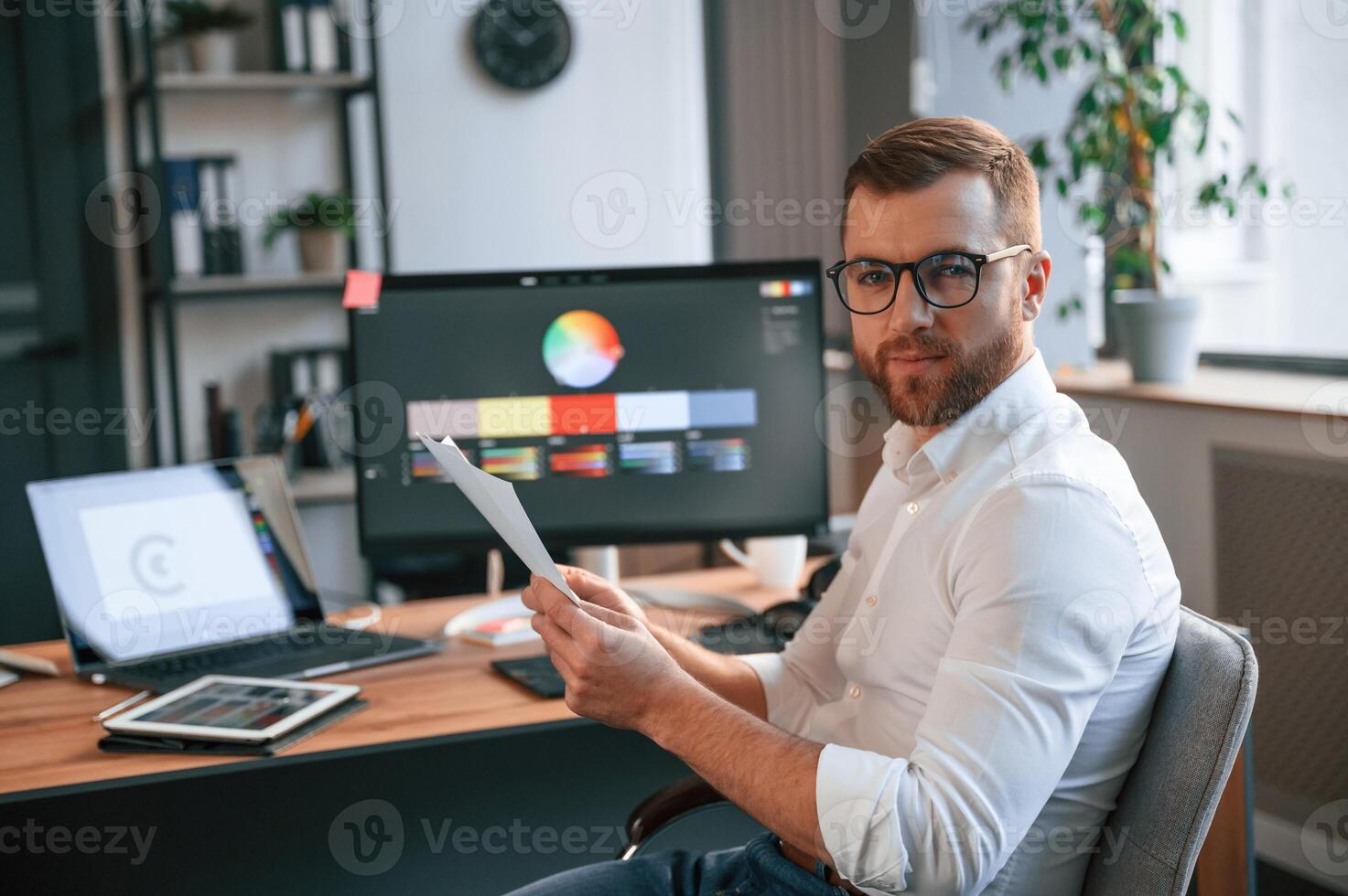 Graphic designer is sitting.. Man, in formal clothes is working in the modern office. Using computer photo