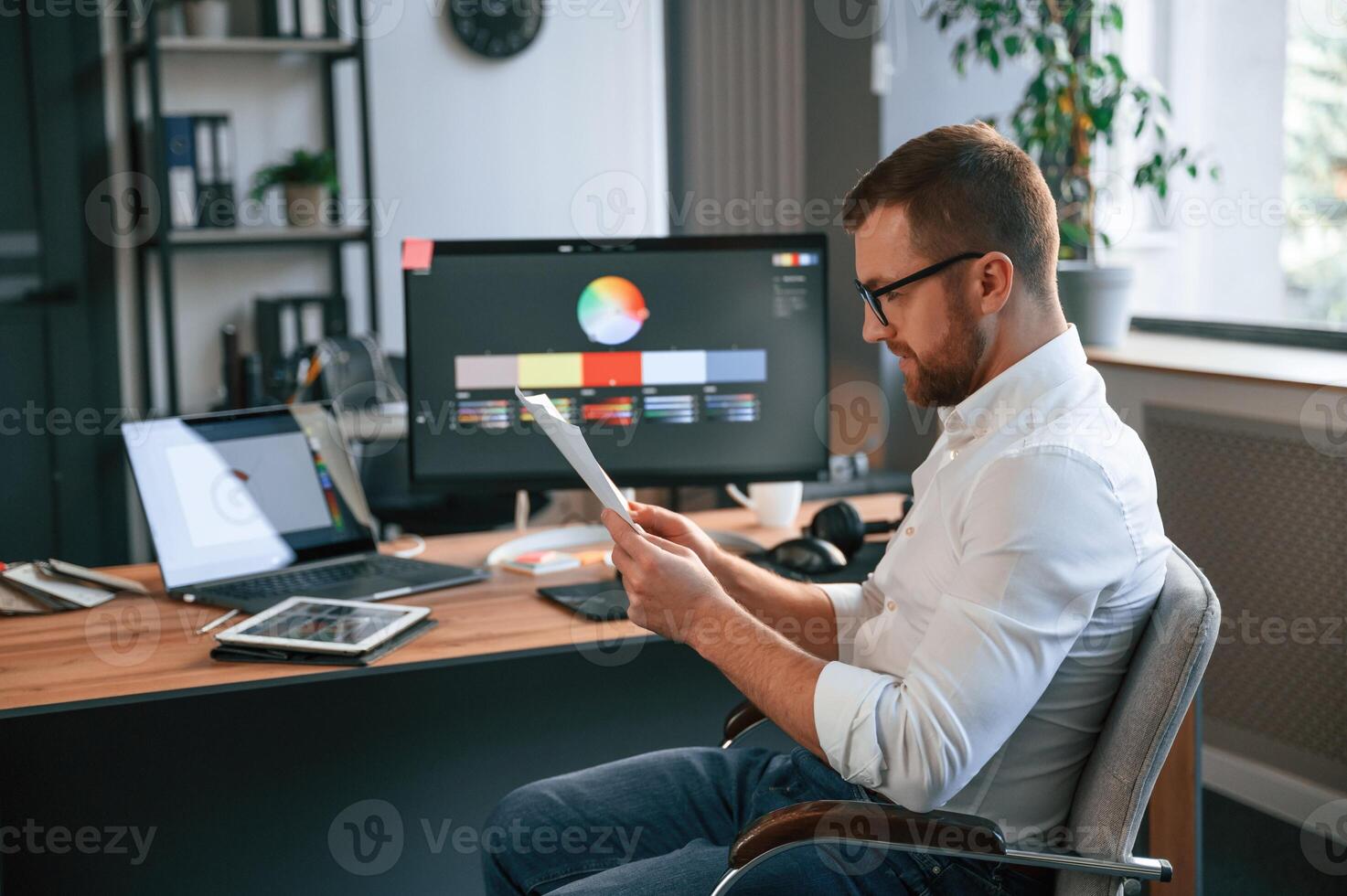 Graphic designer is sitting. Man in formal clothes is ,working in the modern office. Using computer photo