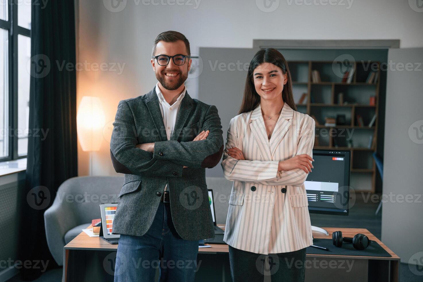 Standing with, arms crossed. Two employees are working together in the modern office photo