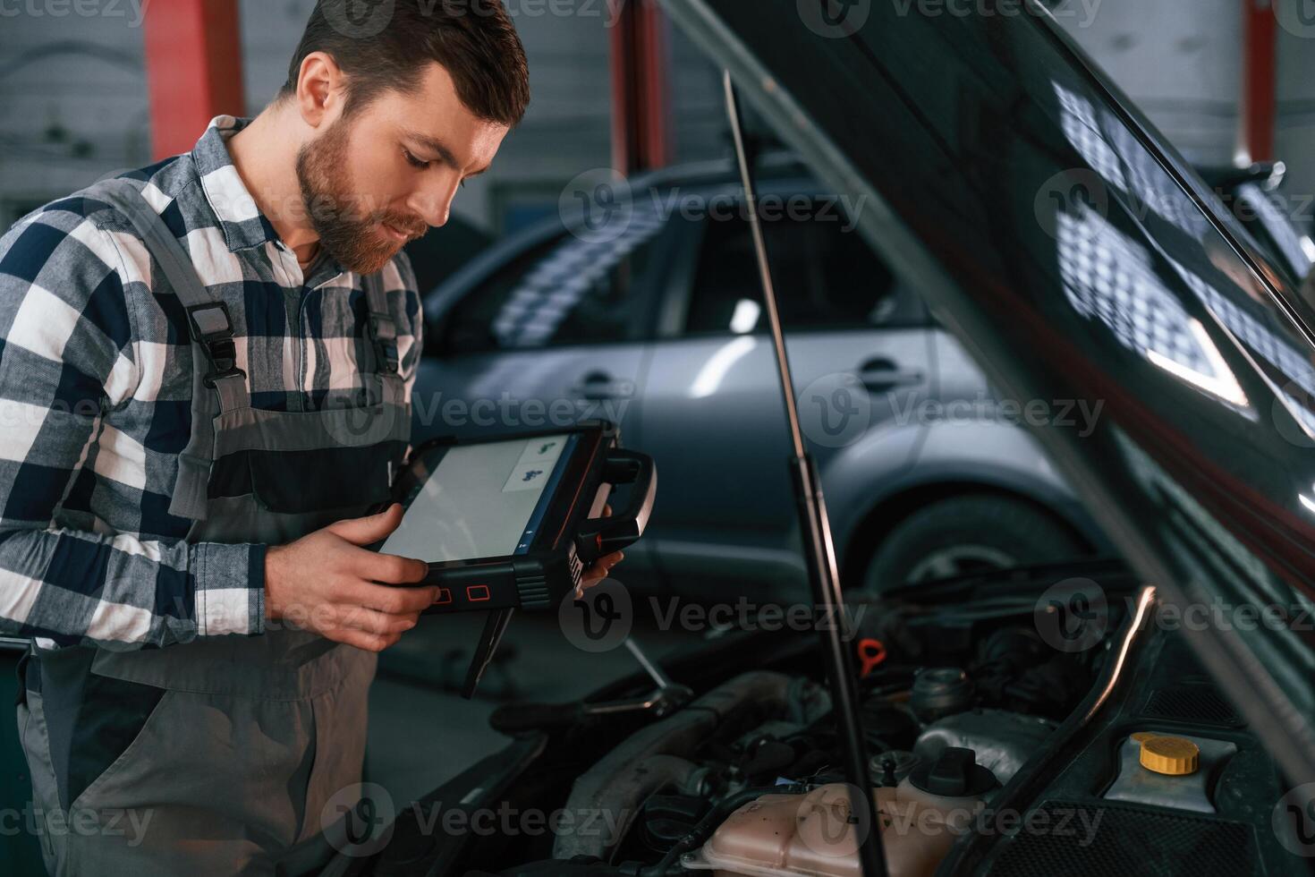 With, tablet in ,hands. Man in uniform is working in the auto salon photo