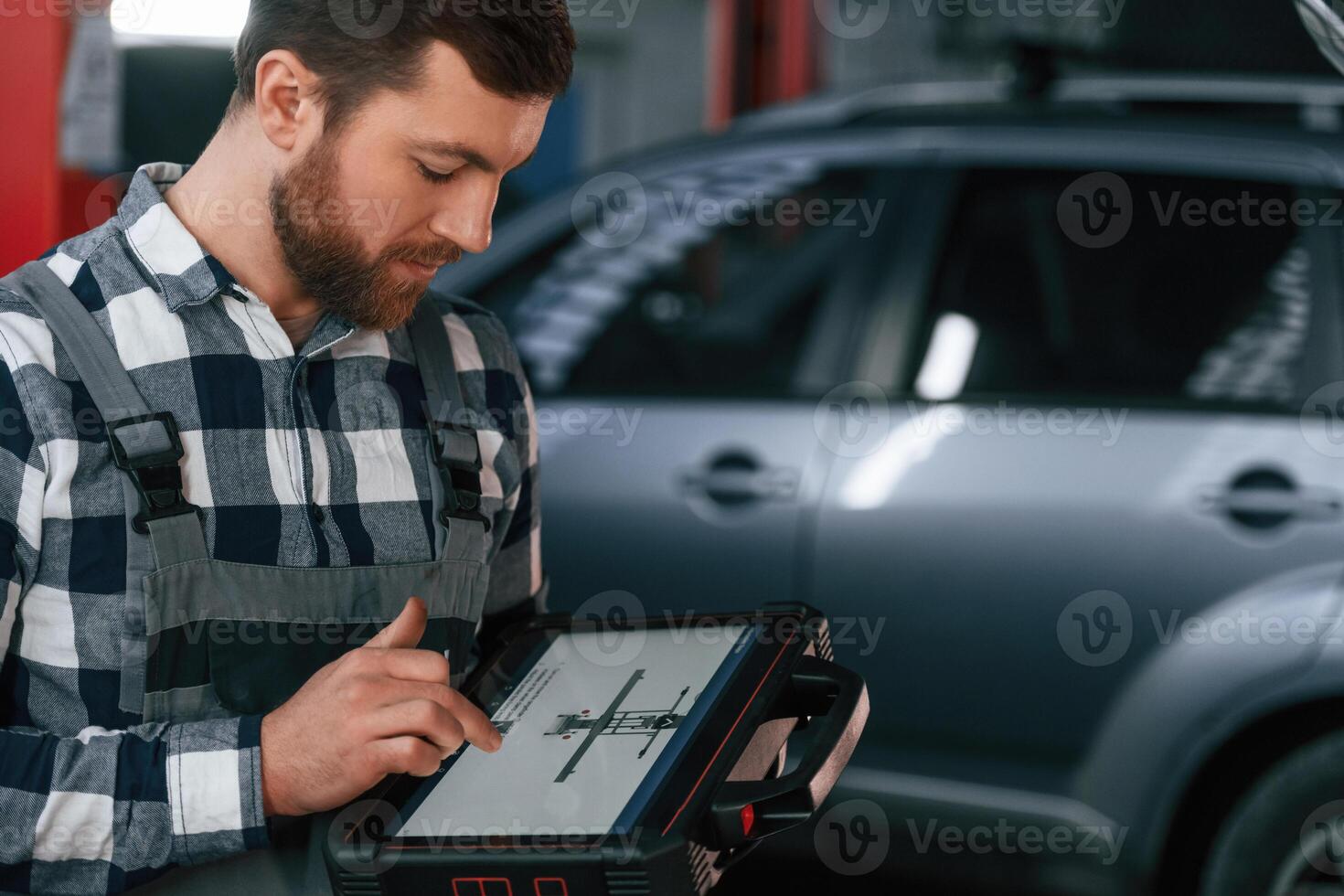 Graphic information is on the, tablet. Man in uniform is working in the auto salon photo