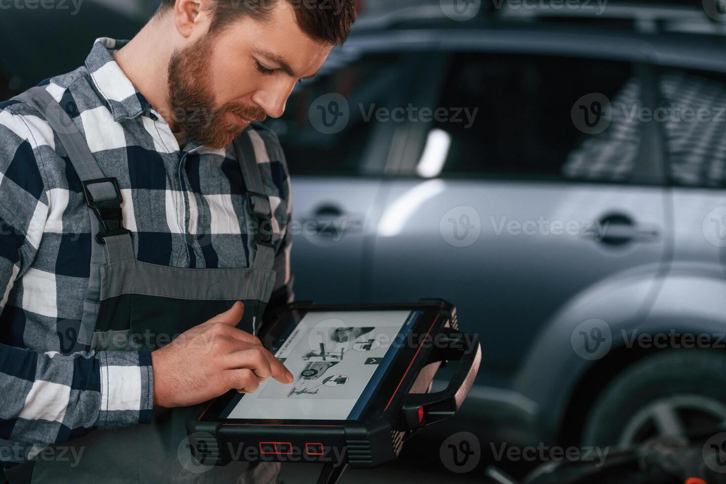 Graphic ,information, is on the tablet. Man in uniform is working in the auto salon photo