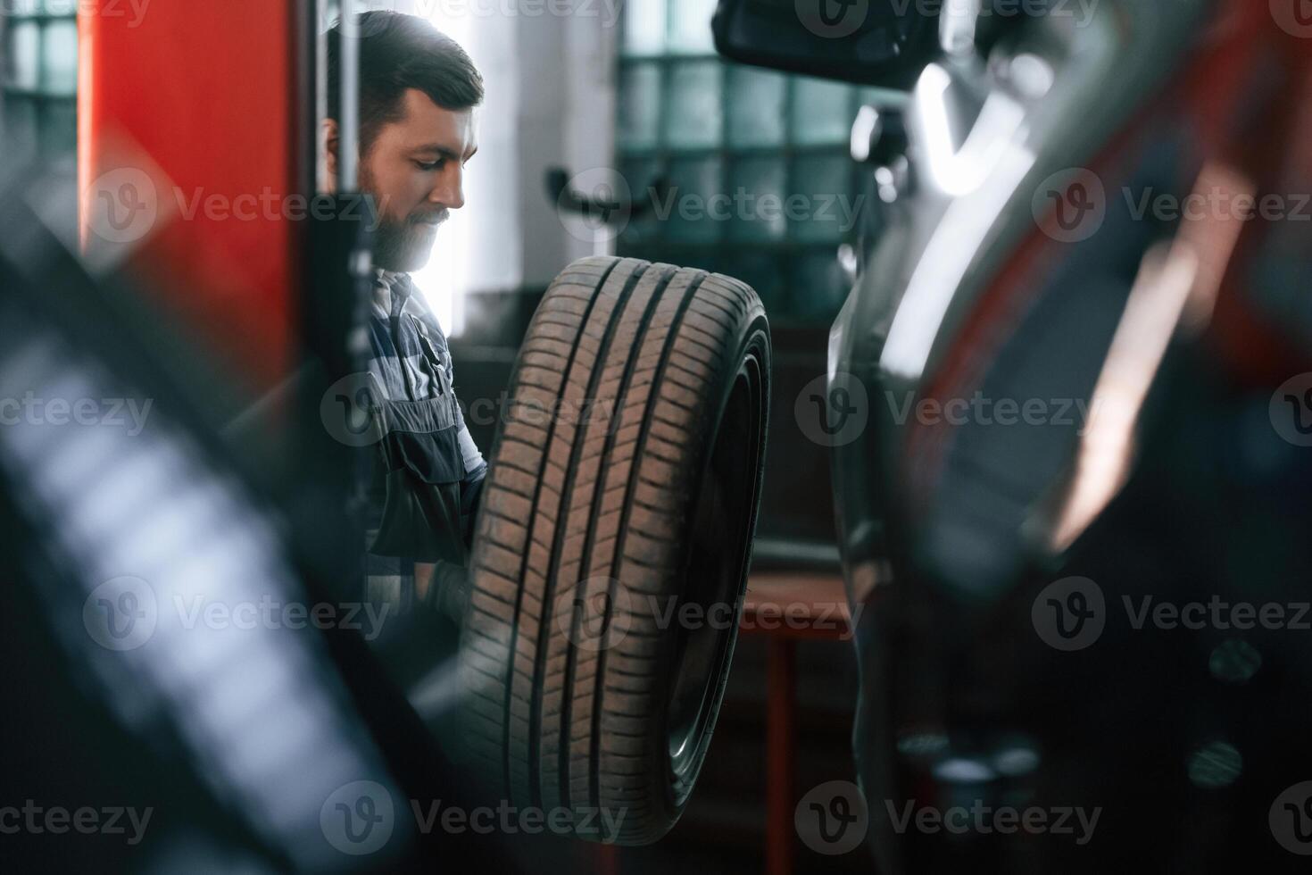 Changing the tire of the, car. Man in uniform is working in the auto salon photo