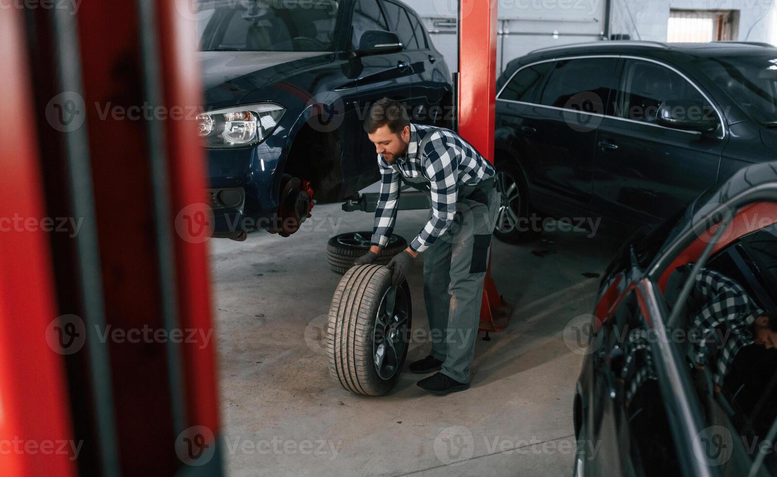Front, left ,wheel is changing. Man in uniform is working in the auto salon photo