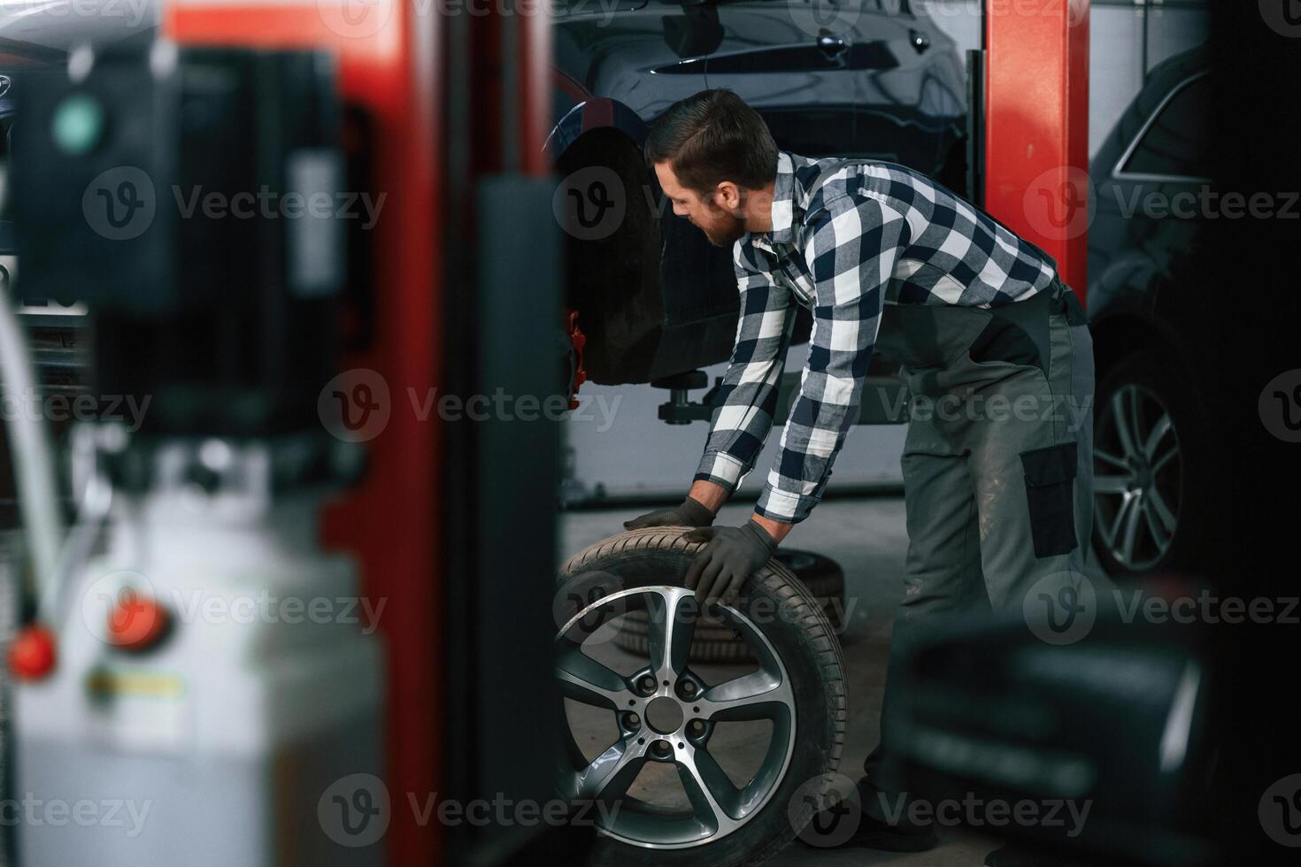 Moving the new, tire for a car. Man in uniform is working in the auto salon photo
