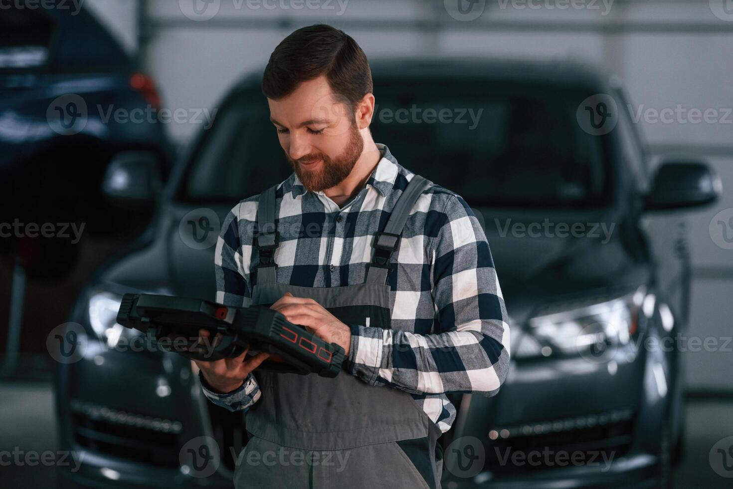 Holding tablet... Man in uniform is working in the auto salon photo