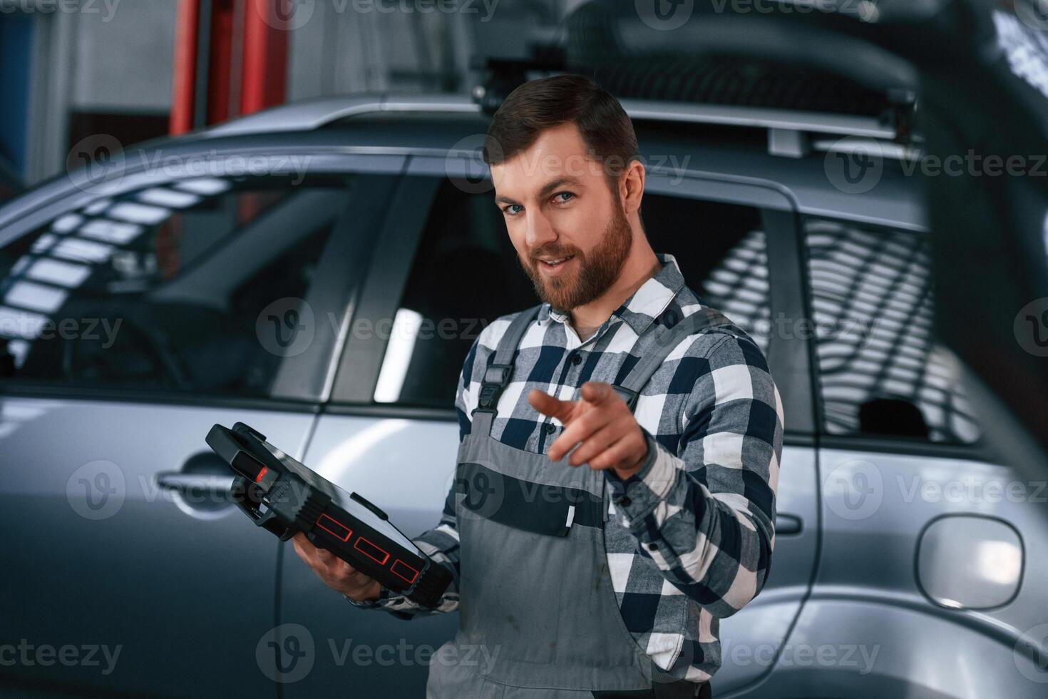 Holding tablet.. Man in uniform is working in the auto salon photo