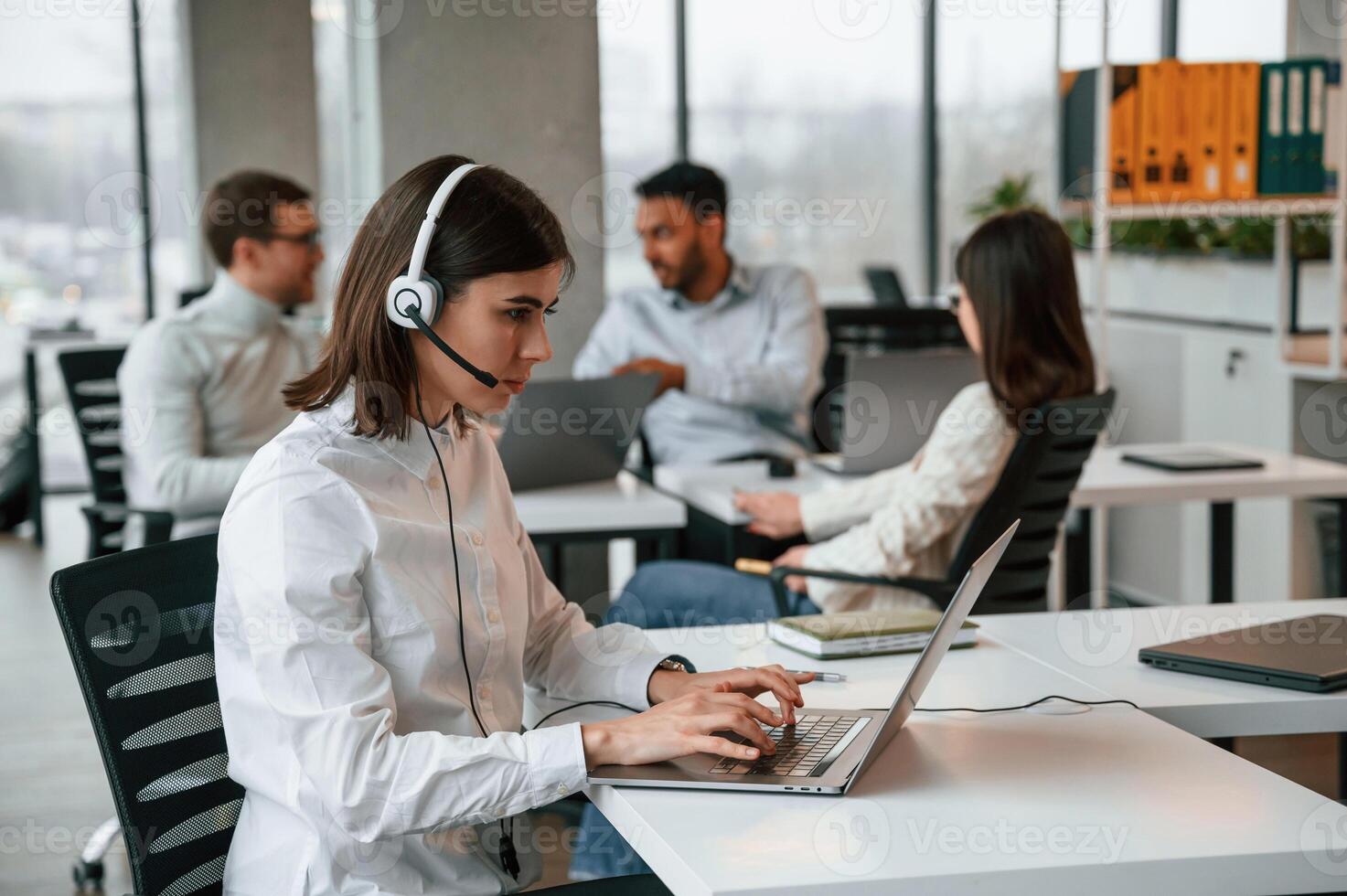 Woman is working by laptop.. Four, people are working in the office together photo