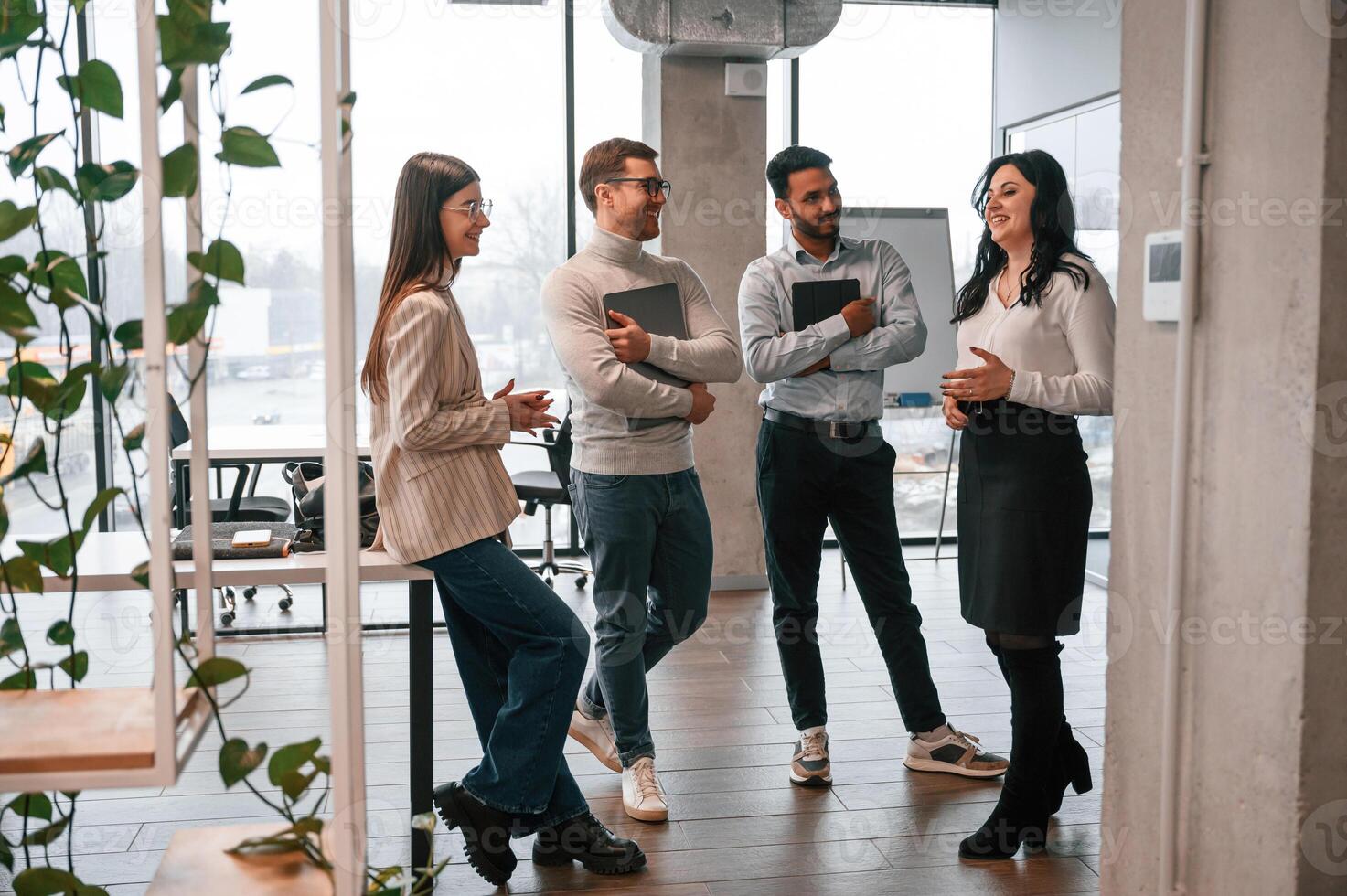 Four people ,standing ,in the office and working together photo