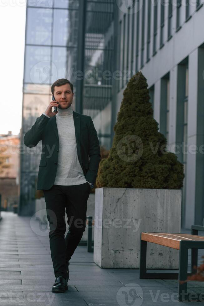 Windows, behind, the handsome man that is in the formal clothes using smartphone photo