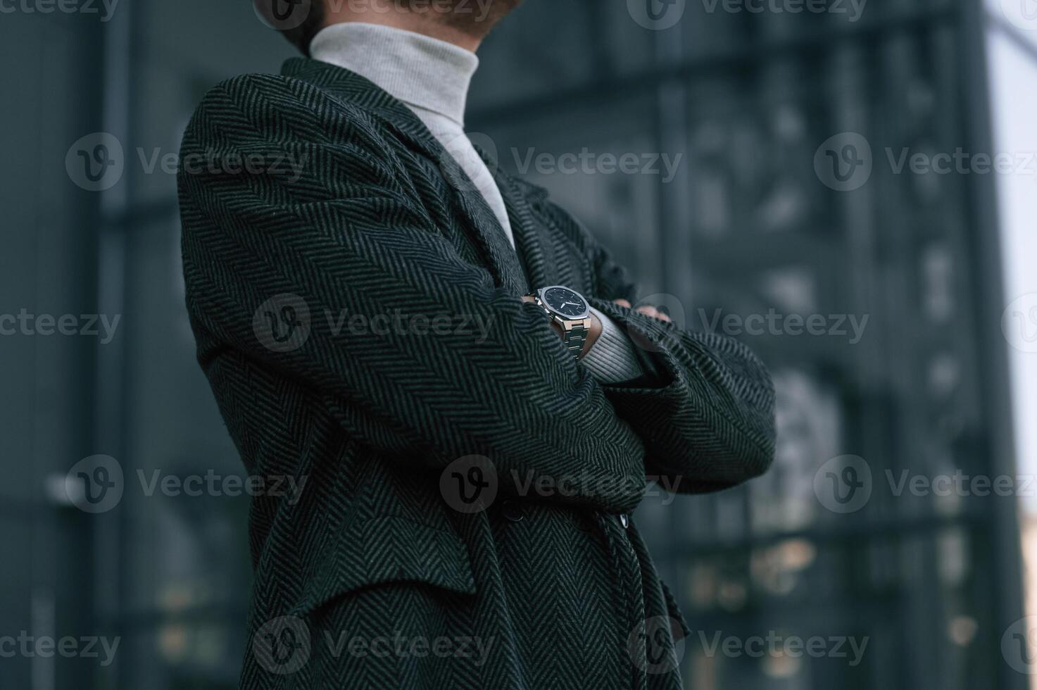 Close up view of businessman that is standing outdoors in the city with arms crossed photo