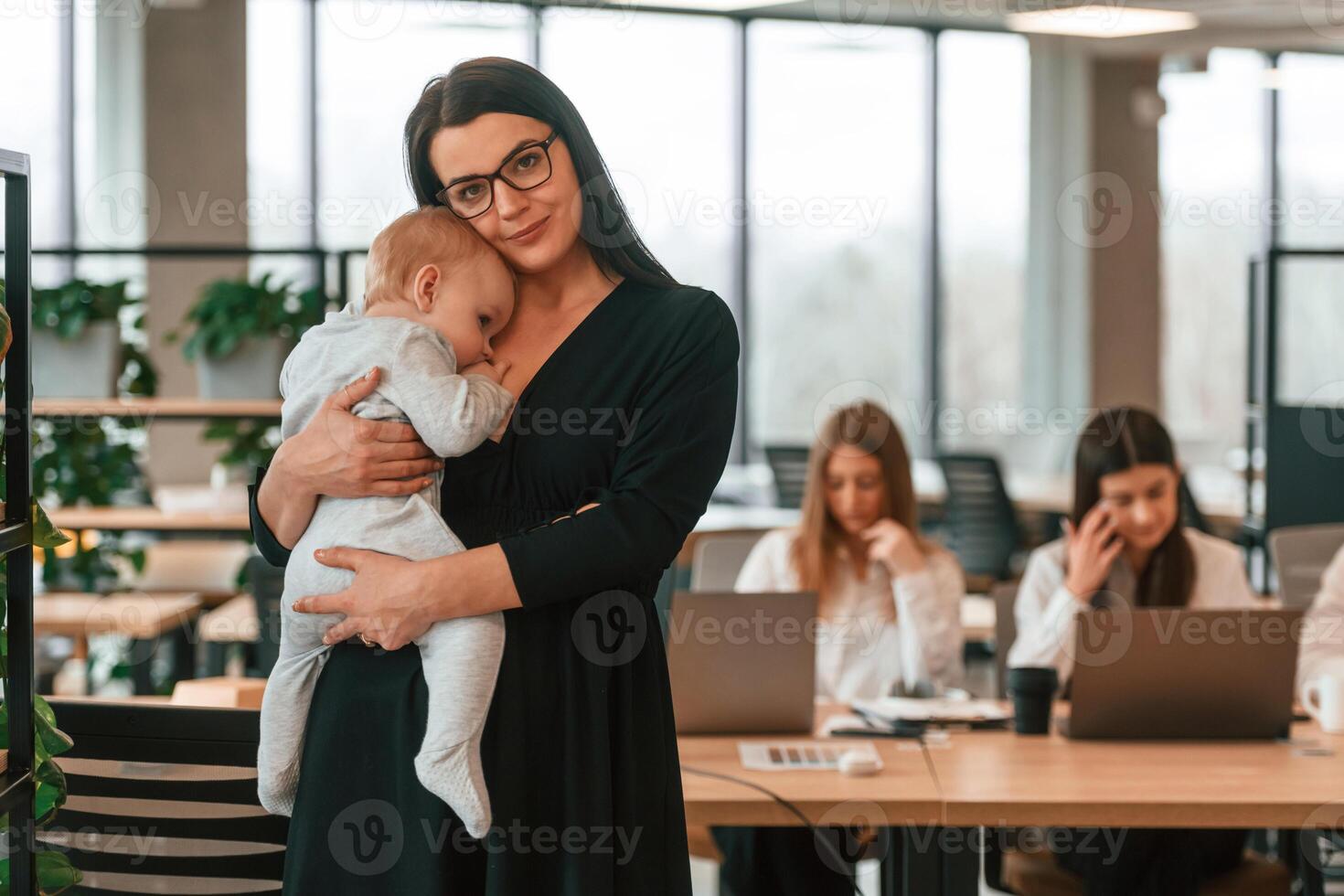 Infant, baby is in the office where group of people are working together photo
