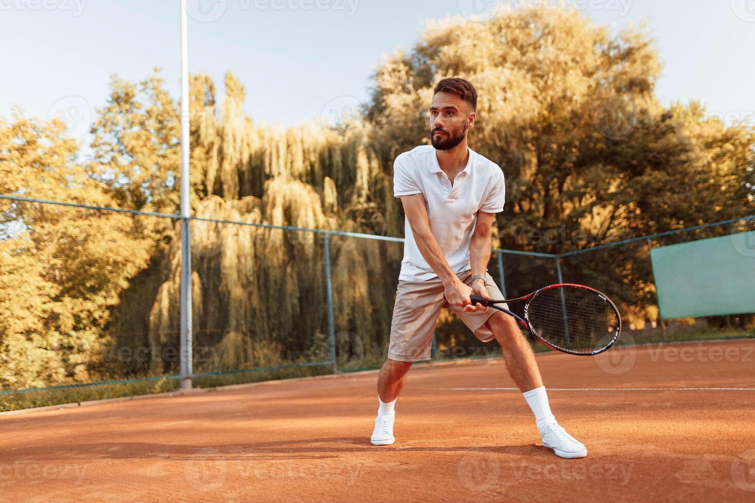 Active training. Young, man is on the tennis court at sunny daytime photo