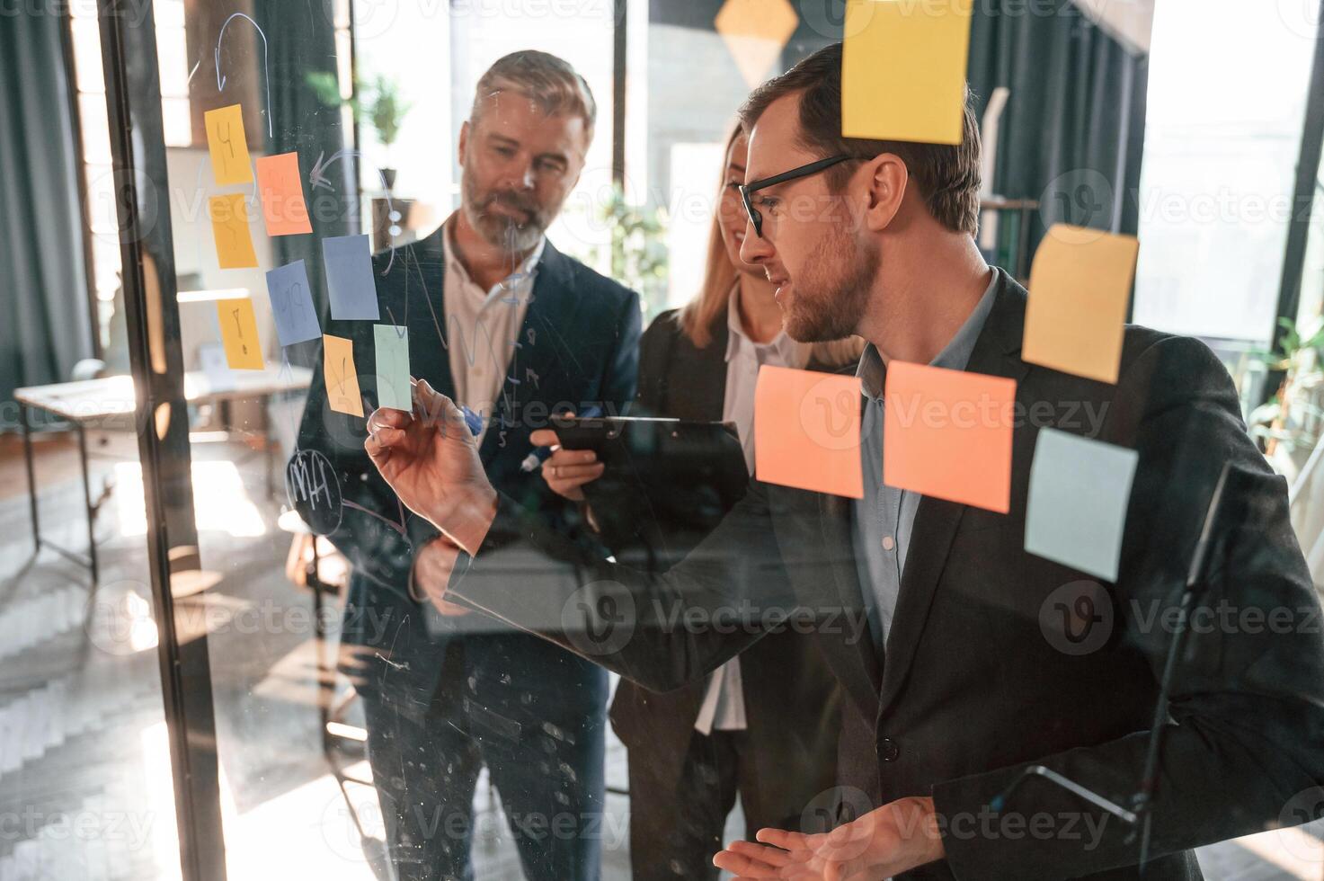 Bunch ,of the stickers, are on the glass. Group of business people are working in the modern office photo