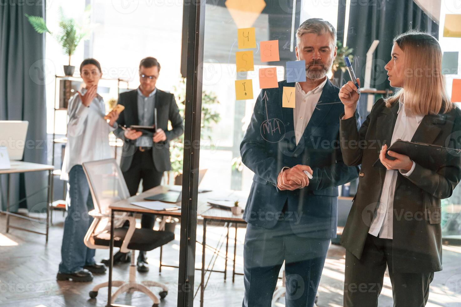 Conception, of plan. Many stickers are on the glass. Group of business people are working in the modern office photo