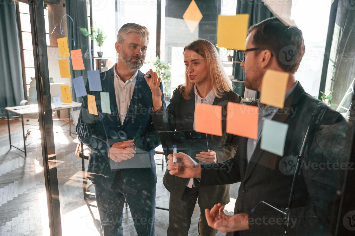 Bunch of the stickers are, on the glass. Group of business people are working in the modern office photo